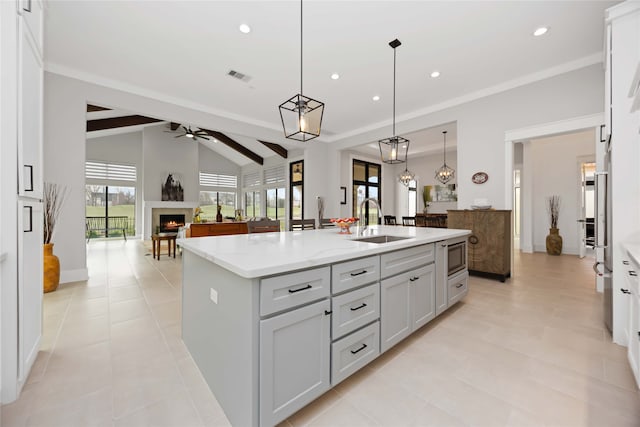 kitchen with a warm lit fireplace, visible vents, a sink, and open floor plan