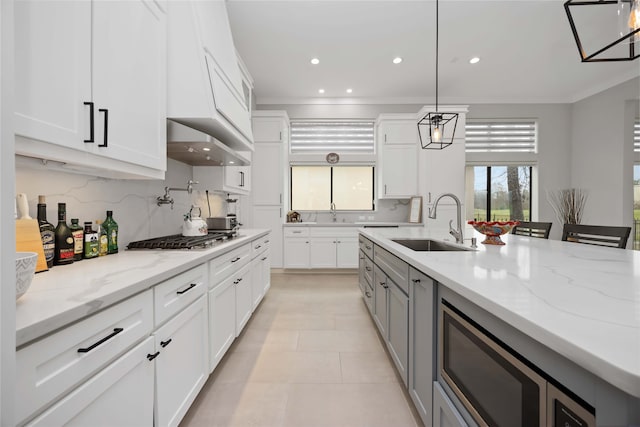 kitchen featuring white cabinetry, stainless steel appliances, a sink, and decorative light fixtures