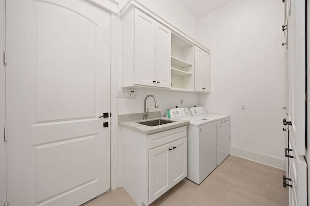 washroom with washer and clothes dryer, a sink, cabinet space, and baseboards