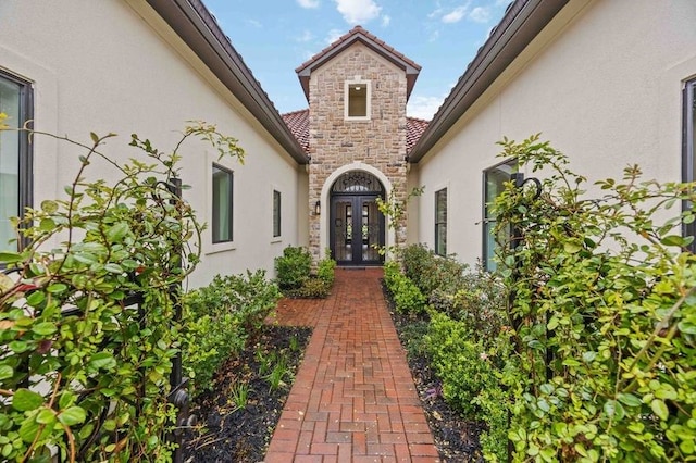 property entrance featuring stone siding, stucco siding, and french doors