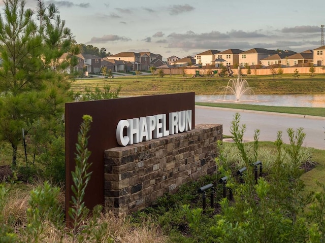 community sign featuring a water view and a residential view