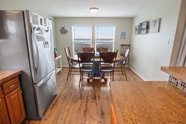 dining room featuring light wood-style flooring and baseboards