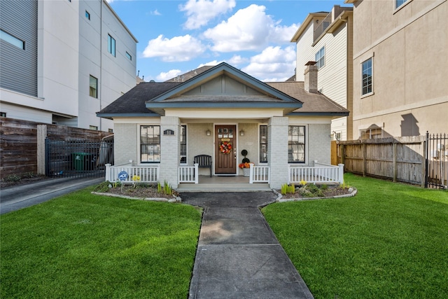 view of front of home featuring a front lawn, fence, a porch, and brick siding