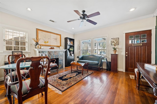 living room featuring wood-type flooring, a high end fireplace, visible vents, and crown molding