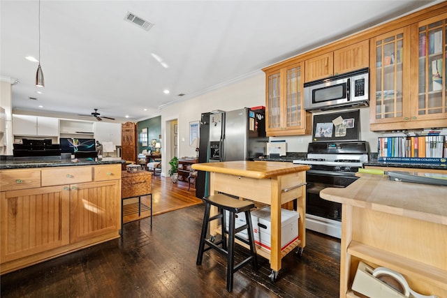 kitchen featuring dark wood-type flooring, visible vents, ornamental molding, stainless steel microwave, and gas stove