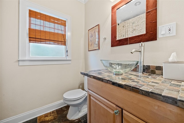 bathroom featuring toilet, vanity, and baseboards