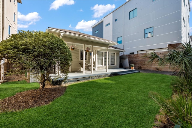 rear view of property with fence and a lawn