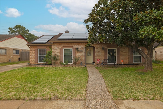 single story home with a front lawn, solar panels, and brick siding