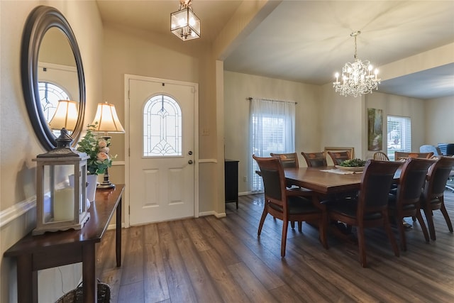 dining space with dark wood-style floors, a chandelier, a wealth of natural light, and baseboards