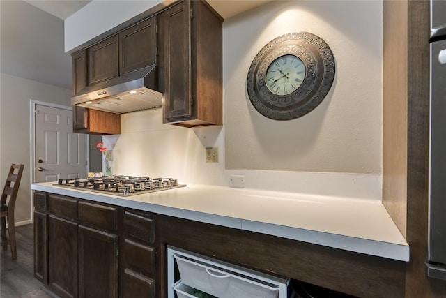 kitchen with a warming drawer, light countertops, stainless steel gas stovetop, dark brown cabinetry, and under cabinet range hood