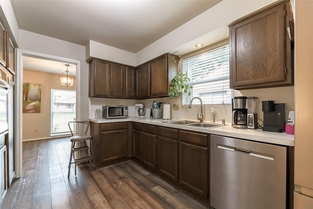 kitchen featuring plenty of natural light, dark wood finished floors, dishwasher, light countertops, and a sink