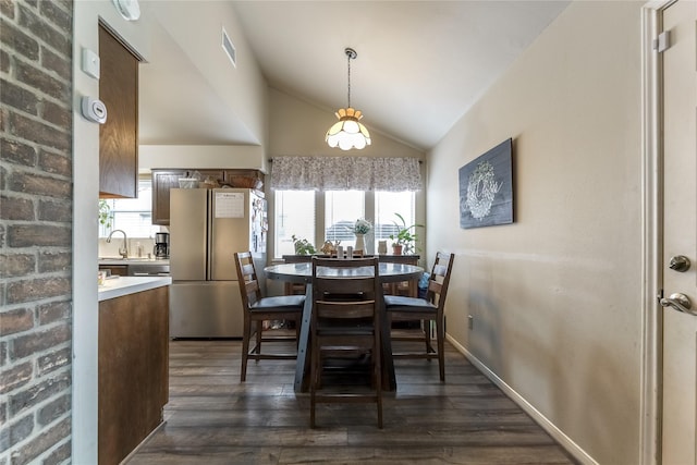 dining space featuring dark wood finished floors, visible vents, vaulted ceiling, and a wealth of natural light