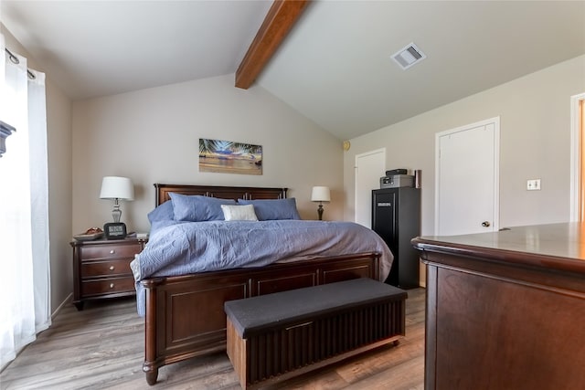 bedroom with lofted ceiling with beams, light wood finished floors, and visible vents