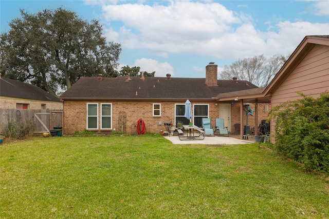 rear view of house with brick siding, a yard, a patio, a chimney, and fence