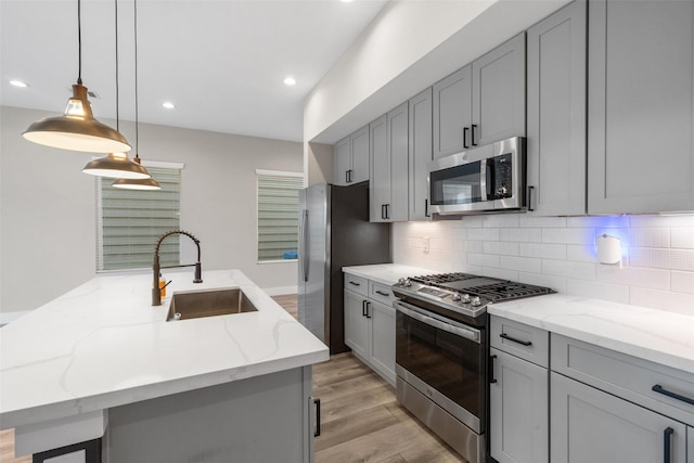 kitchen featuring decorative backsplash, appliances with stainless steel finishes, gray cabinets, and a sink