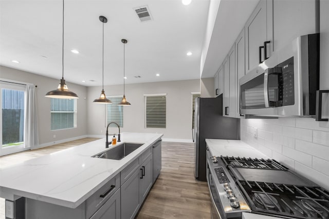 kitchen with visible vents, light wood-style flooring, appliances with stainless steel finishes, gray cabinets, and a sink