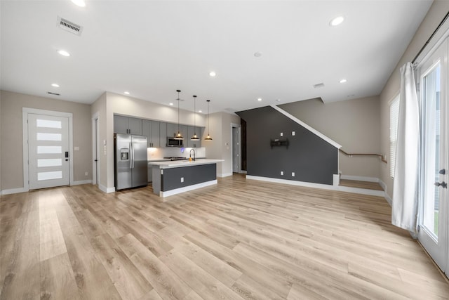 unfurnished living room featuring a wealth of natural light, light wood-style flooring, visible vents, and recessed lighting