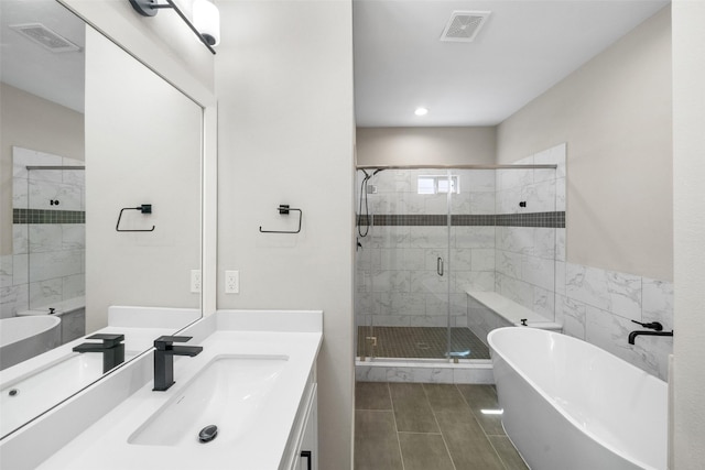 bathroom featuring a stall shower, visible vents, a freestanding bath, and vanity