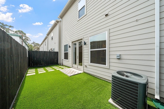 back of house with french doors, a fenced backyard, a lawn, and central air condition unit