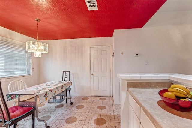 dining space featuring visible vents, a textured ceiling, an inviting chandelier, and light tile patterned floors