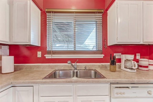 kitchen featuring light countertops, a sink, dishwashing machine, and white cabinetry