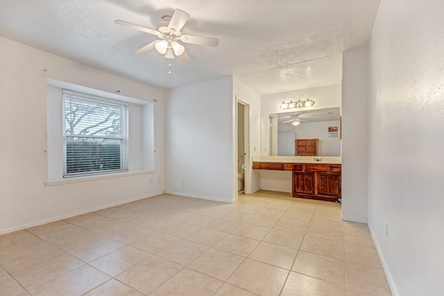 interior space featuring ceiling fan, a textured ceiling, and baseboards