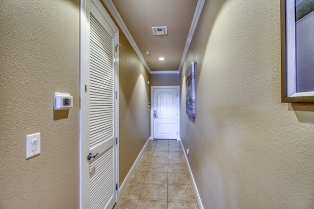 hall with visible vents, a textured wall, ornamental molding, light tile patterned flooring, and baseboards