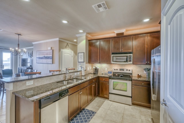 kitchen featuring visible vents, appliances with stainless steel finishes, a peninsula, a sink, and backsplash