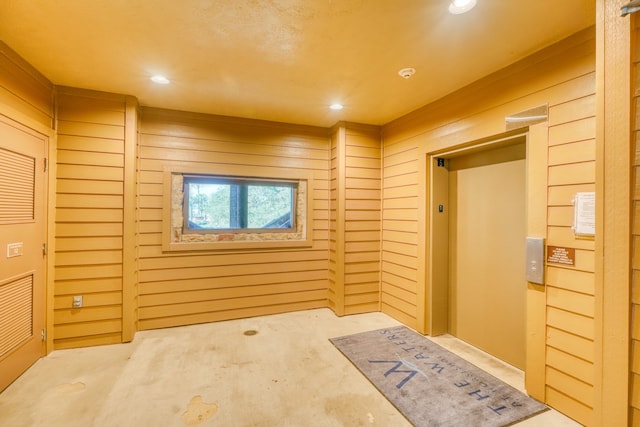 interior space with wood walls, elevator, and recessed lighting