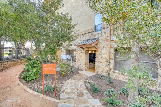 exterior space featuring stone siding, fence, metal roof, and a standing seam roof