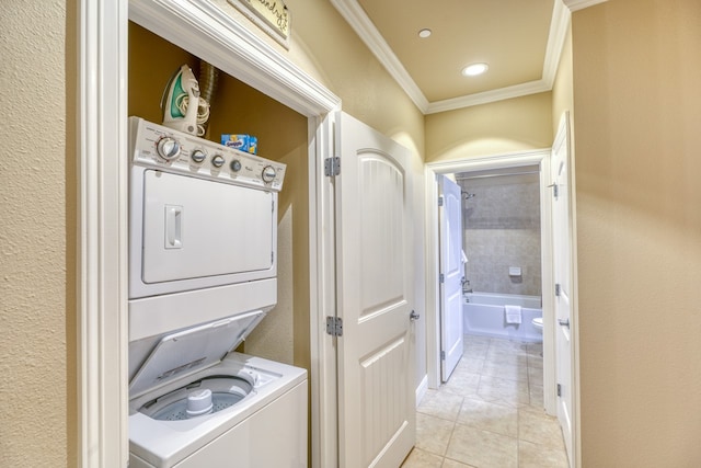 laundry area featuring laundry area, light tile patterned floors, crown molding, and stacked washer and clothes dryer