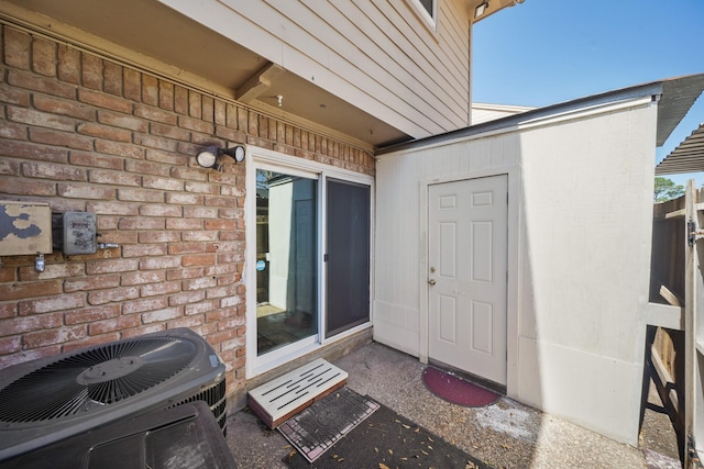 doorway to property featuring brick siding and central air condition unit