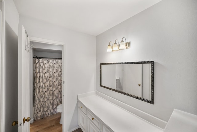 full bathroom featuring toilet, curtained shower, wood finished floors, and vanity