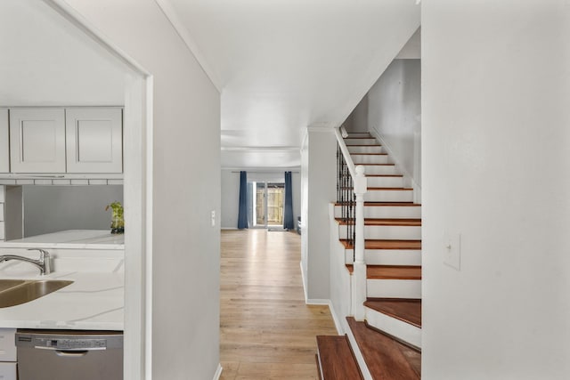 interior space with baseboards, a sink, stairway, and light wood finished floors