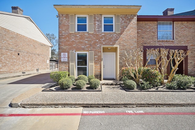 view of front of property featuring brick siding and a chimney