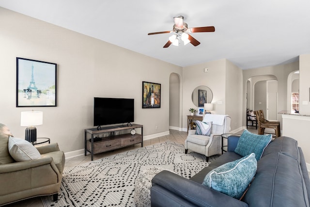 living area with light tile patterned floors, baseboards, and arched walkways