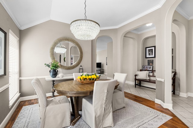 dining space featuring a notable chandelier, lofted ceiling, ornamental molding, wood finished floors, and baseboards