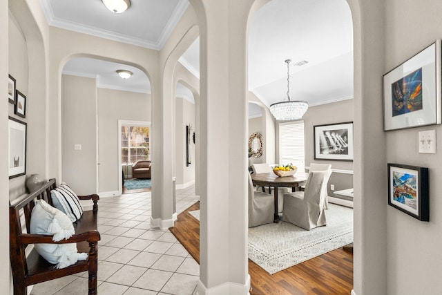 corridor featuring visible vents, arched walkways, crown molding, light tile patterned floors, and baseboards