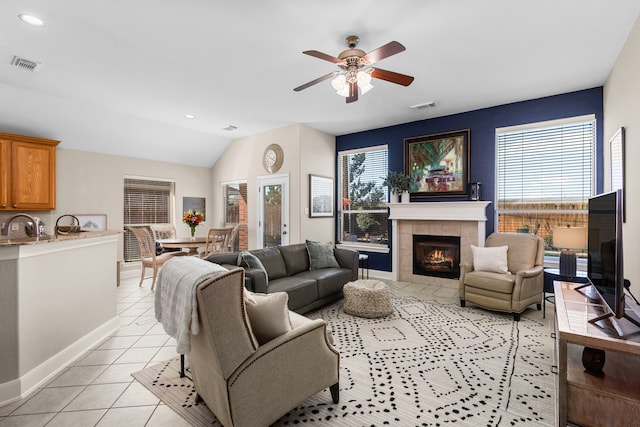 living room with vaulted ceiling, light tile patterned flooring, visible vents, and a tile fireplace