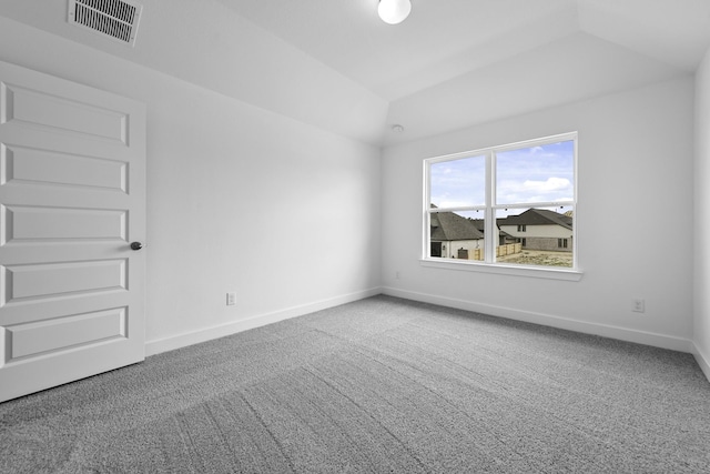 carpeted empty room featuring lofted ceiling, a tray ceiling, visible vents, and baseboards