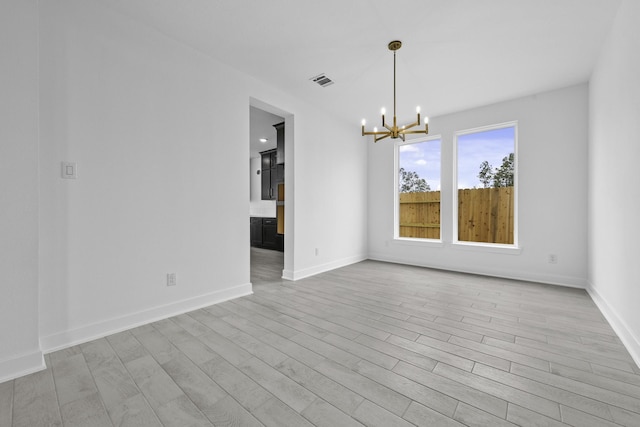 interior space featuring baseboards, wood finished floors, visible vents, and a notable chandelier