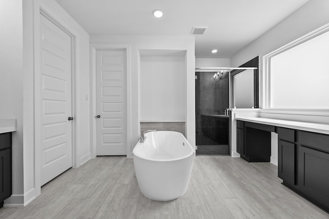 bathroom featuring visible vents, a freestanding bath, a stall shower, vanity, and wood finished floors