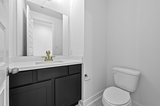 bathroom with baseboards, vanity, and toilet