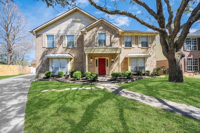 view of front of home with brick siding, a front lawn, and fence