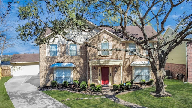 traditional-style home with a garage, a front yard, and brick siding