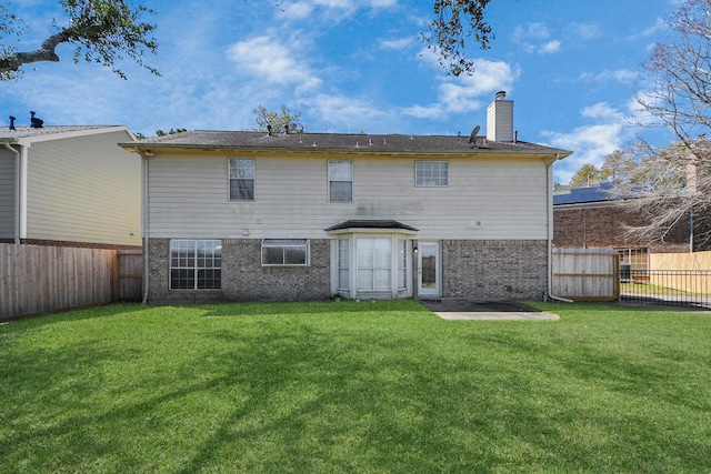 rear view of property featuring a yard, brick siding, a chimney, and a fenced backyard