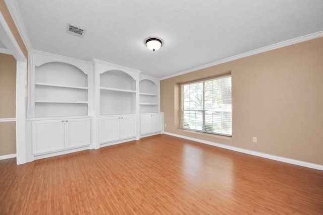 empty room featuring light wood-style flooring, visible vents, baseboards, and ornamental molding