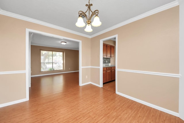 empty room featuring baseboards, ornamental molding, light wood-type flooring, and a notable chandelier