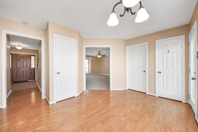 interior space featuring a textured ceiling, light wood-type flooring, and baseboards