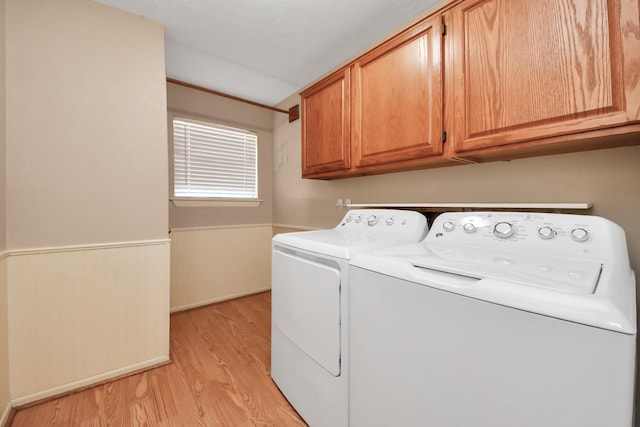 washroom with cabinet space, light wood-style flooring, separate washer and dryer, and a wainscoted wall